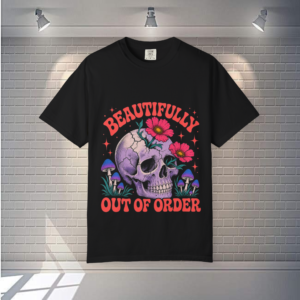 Black t-shirt featuring a purple skull with pink flowers, mushrooms, and the phrase "Beautifully Out of Order.